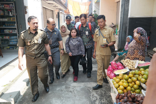 Dyah Anggraeni (tengah) didampingi petugas Kementerian Tenaga Kerja dan P4TKI berjalan menuju rumahnya di Kelurahan Kebalen, Kedungkandang, Kota Malang, Jawa Timur, 19 Februari 2019. (Eko Widianto/BeritaBenar)