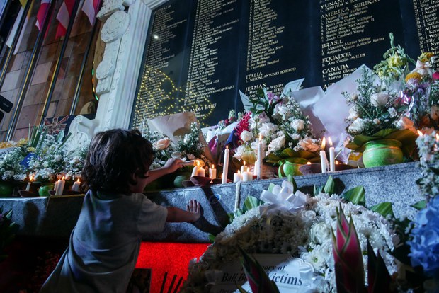 Seorang anak menyalakan lilin di monumen peringatan Bom Bali, 12 Oktober 2022. [Joan Tanamal/BenarNews]