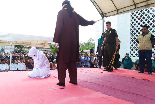 Novia Sri Wahyuni menutup wajahnya ketika dicambuk algojo di Banda Aceh, 19 Januari 2018. (Nurdin Hasan/BeritaBenar)