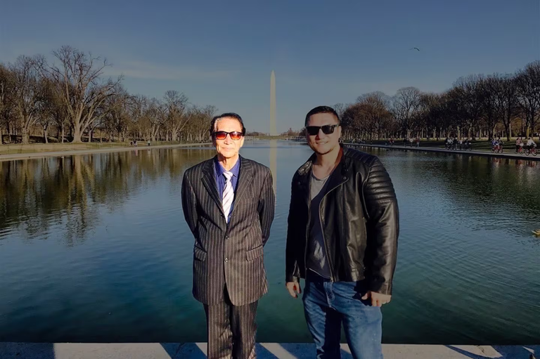Qurban Mamut (kiri), bersama putranya, jurnalis Radio Free Asia Bahram Sintash, dengan latar belakang Monumen Washington di Washington D.C., AS, 2017. [Courtesy dari Bahram Sintash]