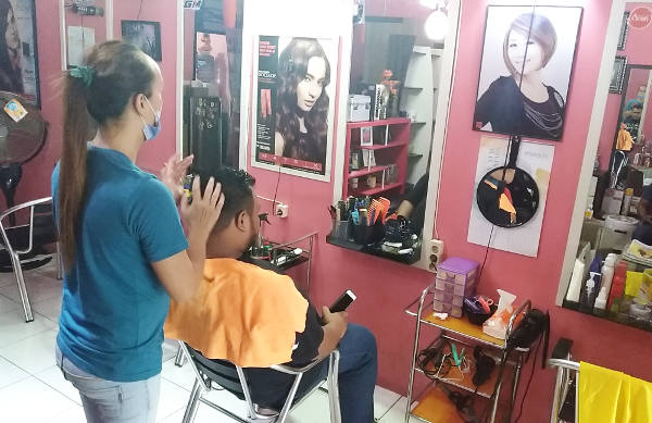 Seorang waria memijat kepala pelanggannya setelah dipangkas rambut di Banda Aceh, 3 Februari 2018. (Nurdin Hasan/BeritaBenar)   