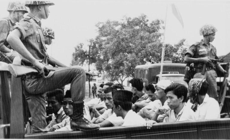 Tentara mengawasi para pemuda anggota Partai Komunis Indonesia (PKI) dalam truk terbuka yang membawa mereka ke penjara di Jakarta, 30 Oktober 1965, setelah penangkapan anggota organisasi yang disebut oleh pemerintah saat itu berada dibalik percobaan kudeta yang menewaskan sejumlah jenderal Angkatan Darat. [Foto File AP]