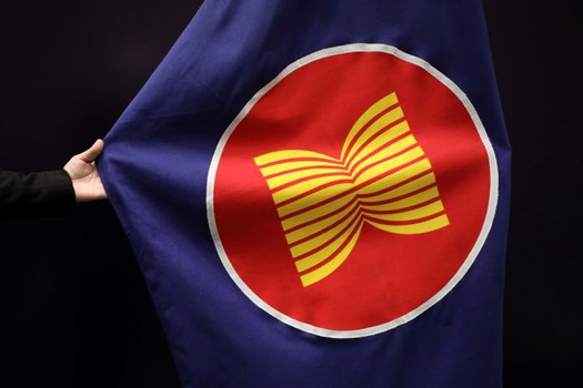 Seorang pekerja memperbaiki letak bendera ASEAN di aula pertemuan di Kuala Lumpur, 28 Oktober 2021. [Reuters]