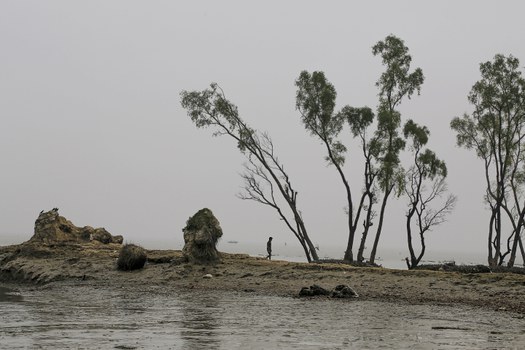Seorang pria berjalan melewati hamparan tanah di mana rumahnya pernah berdiri di Bhola, sebuah pulau di Bangladesh di mana Sungai Meghna mengalir ke Teluk Benggala, 17 November 2015. [AP]