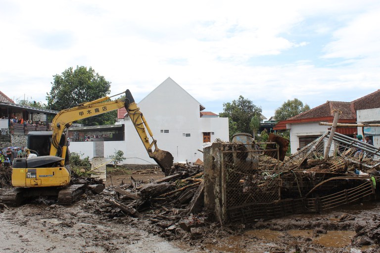 Sebuah escavator membersihkan bekas banjir bandang dan batang pohon raksasa teronggok di pelataran rumah warga, di Kota Batu, Malang, Jawa Timur, 5 November 2021. [Eko Widianto/Benarnews].