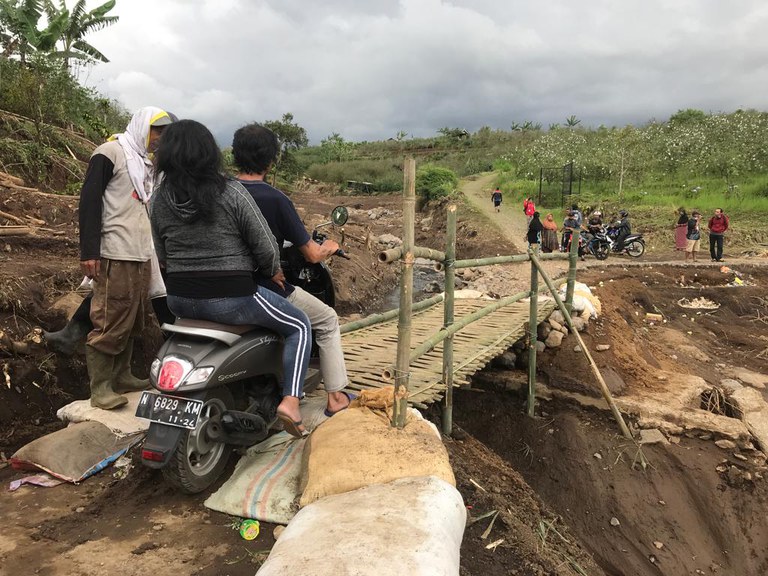 Banjir Bandang Batu 4: Warga setempat melintasi jembatan darurat dari anyaman bambu di atas sungai Paron di Desa Bulukerto, Bumiaji, Kota Batu, Malang, Jawa Timur, setelah jembatan yang menghubungkan antar desa hanyut terseret banjir, 5 November 2021. [Eko Widianto/BenarNews].