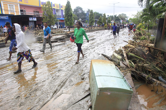 Warga berjalan di jalan berlumpur usai dihantam banjir bandang di Kota Sentani, Papua, 18 Maret 2019. (Victor Mambor/BeritaBenar)