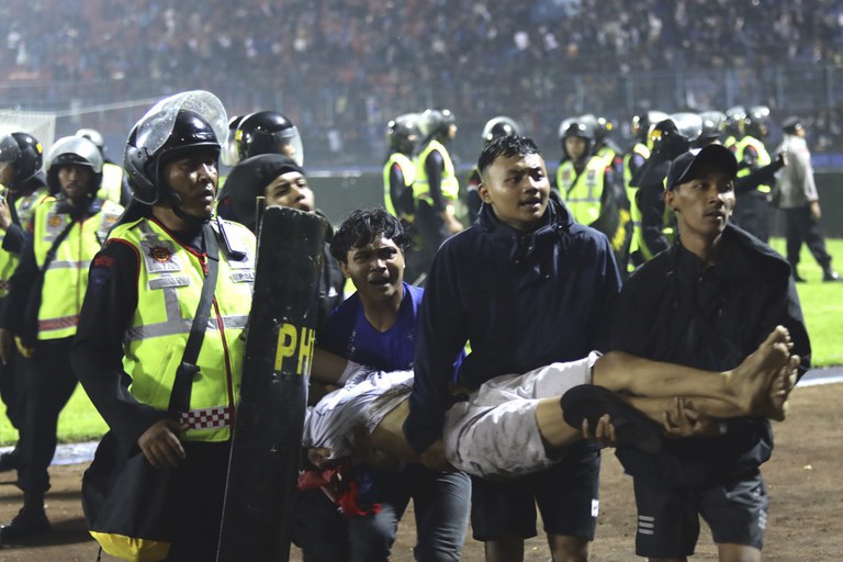 Pendukung sepak bola membawa seorang pria yang terluka setelah terjadi kerusuhan saat pertandingan di Stadion Kanjuruhan di Malang, Jawa Timur, 1 Oktober 2022. [Yudha Prabowo/AP Photo, File]