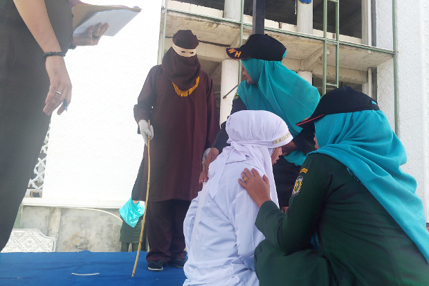 Petugas Wilayatul Hisbah berusaha menenangkan seorang perempuan yang menangis kesakitan saat dicambuk di Banda Aceh, 1 Agustus 2019. (Nurdin Hasan/BeritaBenar)