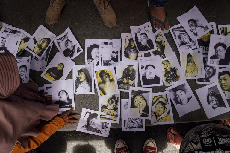 Para keluarga dan handai taulan memeriksa foto-foto korban kerusuhan pertandingan sepak bola yang disediakan oleh kelompok relawan di Malang, Jawa Timur, 2 Oktober 2022. [Dicky Bisinglasi/AP]