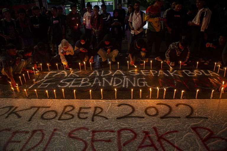 Sejumlah pecinta sepak bola di Palu, Sulawesi Tengah, pada Senin, 3 Oktober 2022, membakar lilin dan menaruhnya di sekeliling spanduk bertuliskan “Tak ada sepak bola yang sebanding nyawa,” saat menggelar aksi mengenang korban tragedi Stadion Kanjuruhan Malang yang menewaskan setidaknya 125 orang dan melukai ratusan lainnya. [Keisyah Aprilia/BenarNews]