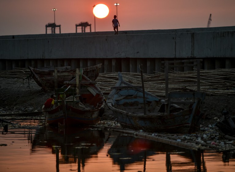 Seorang anak berjalan di atas tanggul laut raksasa yang dibangun untuk melindungi ibu kota dari banjir di tengah naiknya permukaan air laut di Jakarta, 12 Juli 2019. [Bay Ismoyo/AFP]