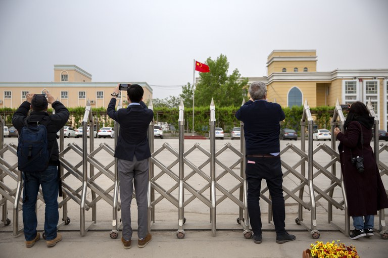 Para wartawan mengambil foto di luar lokasi yang diidentifikasi pada awal 2020 sebagai fasilitas pendidikan, yang menurut pemerintah China adalah rumah bagi biro urusan veteran dan kantor lainnya, di Daerah Otonomi Uyghur Xinjiang China barat, dalam perjalanan yang dibiayai Beijing untuk jurnalis asing, 22 April 2021. [Mark Schiefelbein/AP]