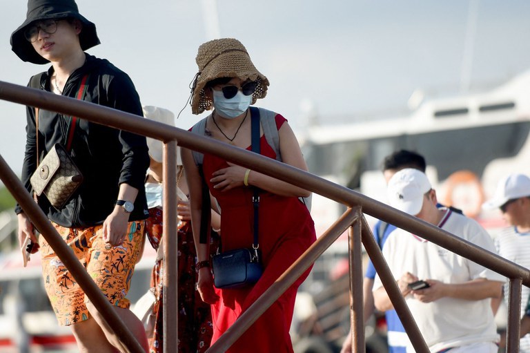Seorang turis Tiongkok (tengah) mengenakan masker tiba bersama turis lain dari Nusa Penida di dermaga kapal cepat di pulau Serangan di Denpasar, Bali, 27 Januari 2020. [Sonny Tumbelaka/AFP]