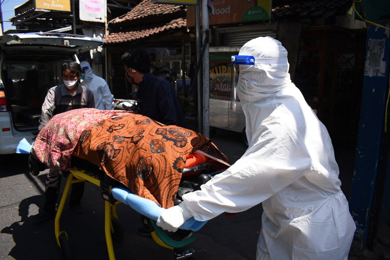 Petugas kesehatan membawa jenazah penderita COVID-19 yang meninggal saat melakukan isolasi mandiri di rumahnya di Bandung, 28 Juli 2021. [AFP]