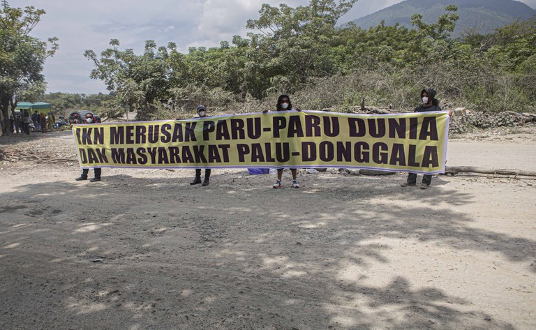 Empat warga yang tergabung dalam Koalisi Petisi Palu-Donggala membentangkan spanduk bertuliskan IKN merusak paru-paru dunia dan masyarakat Palu-Donggala saat menggelar aksi unjuk rasa di lingkar tambang galian C Kelurahan Buluri, Palu, Sulawesi Tengah, 21 Mei 2024. [Taufan Bustan/BenarNews)