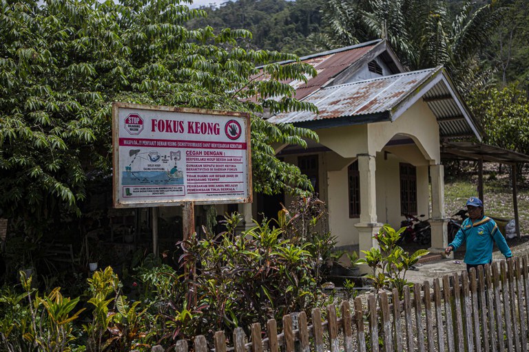 Penanggung jawab Peneliti Schistosomiasis Puskesmas Wuasa, Cerni Tolu, berjalan di dekat papan pemberitahuan fokus keong yang dipasang di pemukiman rumah warga di Desa Watumaeta, Kecamatan Lore Utara, Kabupaten Poso, Sulawesi Tengah, 17 Maret 2023. [Keisyah Aprilia/BenarNews]