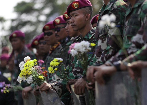 Pasukan marinir yang berjaga di sekitar gedung parlemen memegang bunga yang diberikan oleh para mahasiswa yang berunjuk rasa di Jakarta, 1 Oktober 2019. (AP)