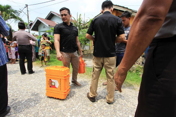 Polisi membawa barang bukti yang telah dimasukkan dalam kotak dari lokasi penggeledahan rumah terduga teroris di Kabupaten Kampar, Riau, 24 Oktober 2017. (Dina Febriastuti/BeritaBenar) 