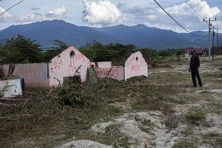 Seorang warga berada di dekat sisa bangunan rumah yang tertimbun lumpur bercampur pasir di Dusun 2, Desa Bangga, Kecamatan Dolo Selatan, Kabupaten Sigi, Sulawesi Tengah, Minggu [15/1/2023). Pangkal bencana yang mengubur rumah-rumah warga di kampung ini adalah guguran material gunung berupa lumpur dan pasir di sekitar hulu sungai yang berjarak tidak jauh dari perkampungan saat hujan. Selain itu dampak dari pembalakan liar di hutan pegunungan memperparah bencana, karena material kayu gelondongan terbawa air bah ke pemukiman penduduk. [Taufan Bustan/BenarNews]