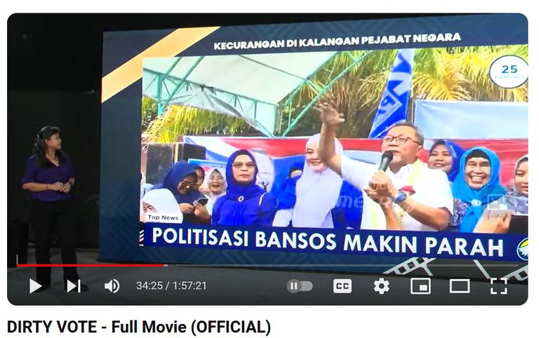 Tangkapan layar yang diambil dari Film Dirty Vote ini memperlihatkan pakar hukum tata negara Bivitri Susanti melihat slide sebuah liputan media terkait bantuan sosia yang bersifat politis yang dibagikan oleh pejabat negara untuk pemenangan salah satu pasangan calon presiden/wakil presiden dalam Pemilu 2024. [Dirty Vote - full movie official via YouTube]