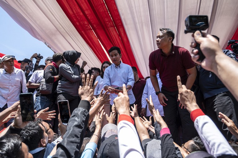 Calon wakil presiden Gibran Rakabuming Raka (tengah), putra Presiden Indonesia Joko Widodo dan Wali Kota Surakarta saat ini, membagikan cendera mata kepada para pendukungnya saat kampanye di Gelora Delta Sidoarjo di Sidoarjo, Jawa Timur, pada 28 Januari 2024. [Juni Kriswanto/AFP]