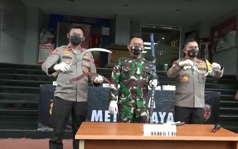 Dalam tangkapan layar video tertangal 7 Desember 2020 ini, seorang polisi dan tentara dalam sebuah konferensi pers di Jakarta memperlihatkan barang bukti yang mereka klaim telah dibawa oleh Front Pembela Islam (FPI) dalam bentrok dengan polisi yang terjadi di jalan tol Jakarta-Cikampek km. 50 yang menewaskan enam anggota FPI. [Reuters]