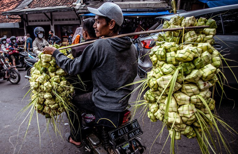 Seorang pria menjual ketupat yang telah berisi beras di dalamnya untuk menyambut Idul Fitri di pasar tradisional di Bogor, Jawa Barat, 30 April 2022. [Aditya Aji/AFP]