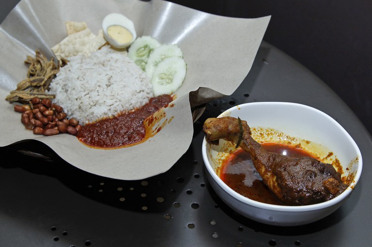 Hidangan favorit Malaysia, nasi Lemak (kiri) dihidangkan di atas meja bersama makanan pelengkapnya di sebuah restoran di Subang Jaya, Malaysia, 3 April 2018. [Sadiq Asyraf/AP]