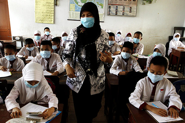 Murid-murid di Palembang, Sumatera Selatan, belajar di kelas dengan menggunakan masker October 8, 2015. 