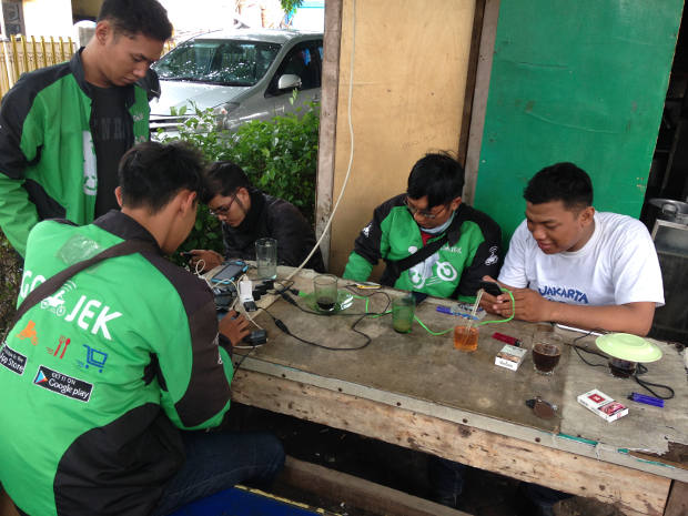 Pengemudi Gojek, menunggu order sambil memperhatikan telepon pintar mereka di tempat mangkal mereka di Jakarta, 18 Desember 2015. (BeritaBenar)