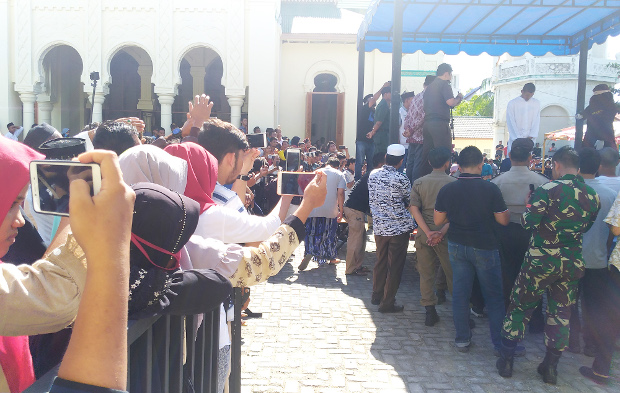 Warga merekam prosesi hukuman cambuk terhadap pelaku pelanggaran syariat Islam di halaman sebuah masjid di Banda Aceh, 13 Juli 2018. (Nurdin Hasan/BeritaBenar)
