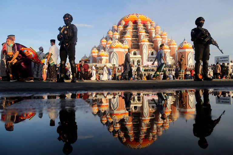 Polisi bersenjata bersiaga saat warga melakukan Salat Id di Makassar, 2 Mei 2022. [AFP]