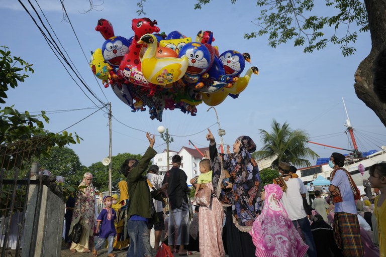 Seorang ibu membeli balon untuk anaknya setelah salat Idul Fitri di pelabuhan Sunda Kelapa di Jakarta, 2 Mei 2022. [AP]