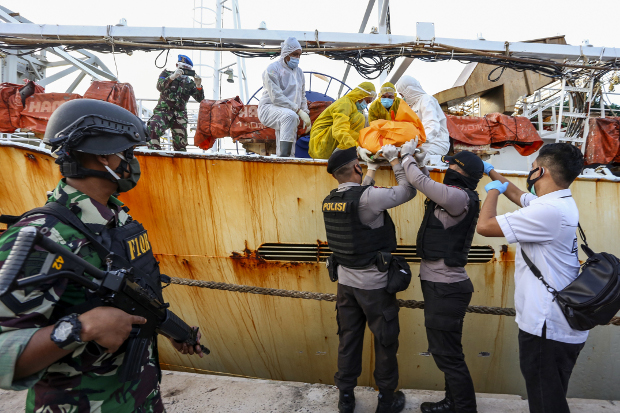 Dalam foto tertanggal 8 Juli 2020 ini, petugas menurunkan seorang mayat pekerja asal Indonesia yang meninggal saat bekerja di kapal penangkap ikan Cina, setelah kapal tersebut ditangkap di wilayah Batam, Kepulauan Riau. [AFP]