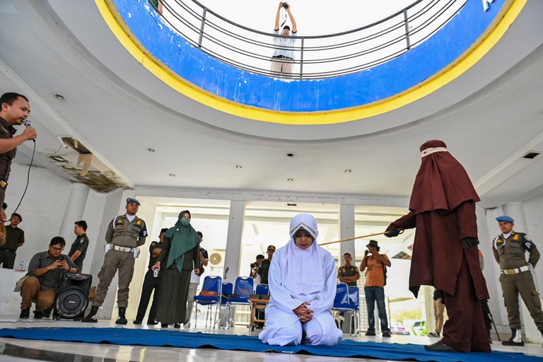 Seorang perempuan dicambuk sebagai hukuman di bawah aturan Syariah di Provinsi Aceh karena tertangkap berada dekat dengan seorang laki-laki yang bukan anggota keluarganya, pada 20 Maret 2023. Pegiat hak asasi manusia melihat pemberlakuan hukuman cambuk sebagai pelanggaran atas hak asasi manusia. [Chaideer Mahyuddin/AFP]