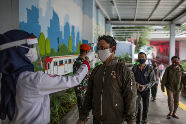 Petugas Stasiun Kereta Komuter memeriksa suhu tubuh calon penumpang di Stasiun Sudirman, Jakarta, 5 Juni 2020. [Afriadi Hikmal/BenarNews]