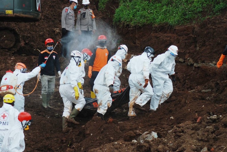 Tim penyelamat didesinfeksi saat mereka mengeluarkan tubuh korban longsor yang menewaskan total 40 orang di Sumedang, Jawa Barat, pada 17 Januari 2021. [AFP]