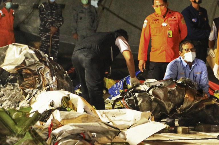 Petugas memeriksa potongan-potongan puing pesawat yang ditemukan dari lokasi jatuhnya penerbangan Sriwijaya Air SJY182, di Pelabuhan Tanjung Priok, Jakarta, 15 Januari 2021. [AFP]