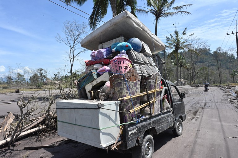 Warga membawa barang-barang yang mereka bisa selamatkan di desa Curah Kobokan di Lumajang, Jawa Timur, pada 7 Desember 2021, pasca letusan Gunung Semeru tiga hari sebelumnya. [AFP]