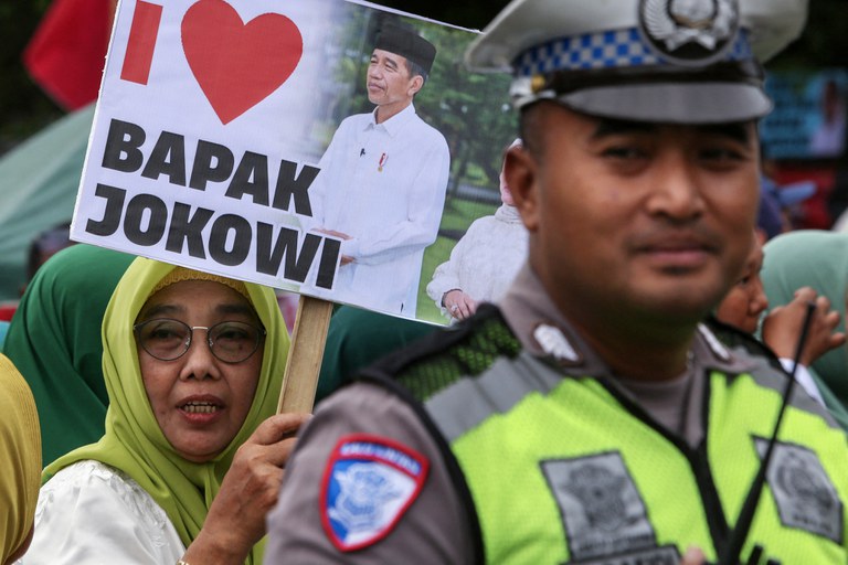 Seorang warga memegang poster saat ia dan ribuan orang lainnya menyambut kepulangan mantan Presiden Indonesia Joko Widodo ke kampung halamannya di Solo, Jawa Tengah, 20 Oktober 2024. [Devi Rahman/AFP]