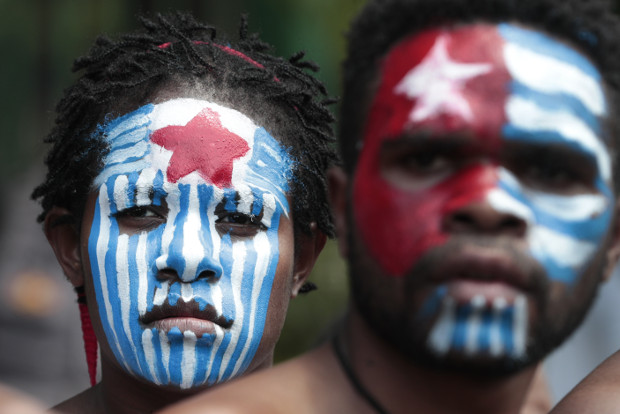 Aktivis Papua mewarnai muka mereka dengan warna lambang Bintang Kejora, simbol gerakan separatis Organisasi Papua Merdeka, saat berdemonstrasi di dekat Istana Negara di Jakarta, 22 Agustus 2019. (AP)