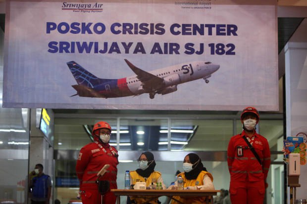 Sejumlah petugas berdiri di depan posko crisis center Sriwijaya Air SJ-182 di Bandara International Soekarno Hatta, Tanggerang, Banten, pada hari pesawat tersebut jatuh di sekitar perairan Kepulauan Seribu di Laut Jawa, 9 Januari 2021. [Araminta JR/BenarNews]