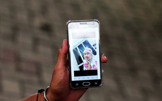 Seorang warga memperlihatkan layar telepon genggamnya yang berisi foto anggota keluarganya yang merupakan penumpang pesawat Sriwijaya Air SJ-182, di pos ante mortem RS Polri Kramat Jati di Jakarta, 12 Januari 2021. [Anhar Rizki Affandi/BenarNews]