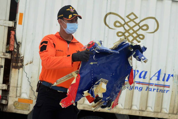 Seorang petugas Basarnas memperlihatkan puing Pesawat Sriwijaya Air SJ-182 untuk dikumpulkan di Pelabuhan Tanjung Priuk, Jakarta Utara, 11 Januari 2021. Puing pesawat ini ditemukan dalam sebuah operasi gabungan oleh Polri, TNI, KNKT, Basarnas, dan potensi SAR lainnya di Perairan Kepulauan Seribu. [Senaru/BenarNews]
