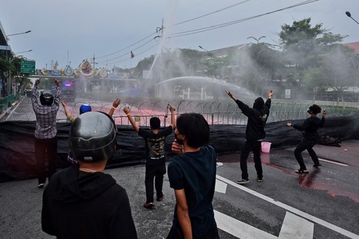 Para pengunjuk rasa menantang aparat keamanan ketika polisi mengerahkan meriam air dalam demonstrasi di Bangkok menuntut pengunduran diri Perdana Menteri Thailand Prayuth Chan-O-Cha atas penanganannya terhadap krisis COVID-19, 25 September 2021. [AFP]