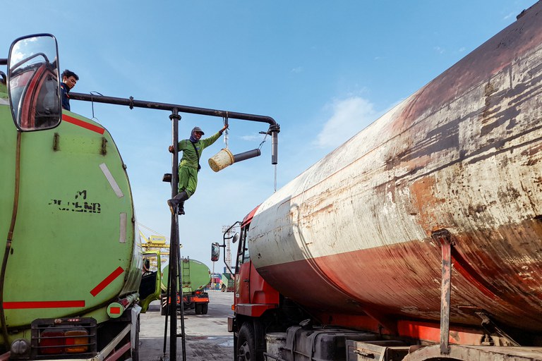 Pekerja memindahkan minyak sawit mentah ke sebuah truk tangki di pelabuhan Tanjung Emas di Semarang untuk dikirim ke pabrik, 7 April 2022. [AFP]