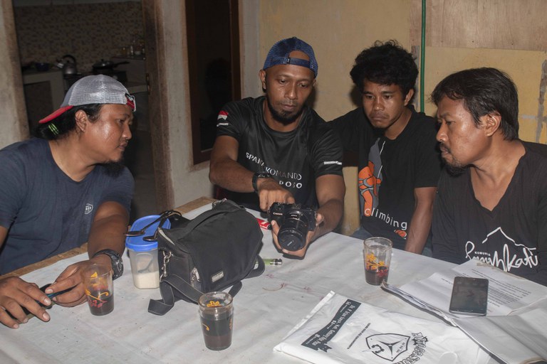 Supriyadi alias Upik Pagar (kiri), dan beberapa pendukung film terkait pentingnya kesadaran atas bahaya radikalisme melihat hasil tampilan footage film tersebut di kamera, seusai shooting di markas Rumah Katu di Mepanga, Poso, Sulawesi Tengah, 22 Juni 2022. [Keisyah Aprilia/BenarNews]