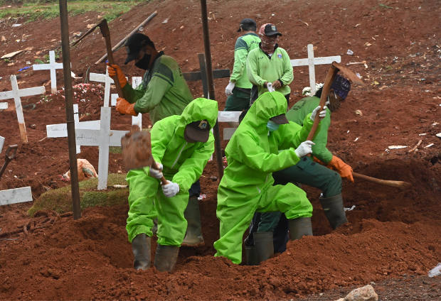 Para penggali kubur, mengenakan pakaian pelindung khusus, tengah bekerja di sebuah kawasan pemakaman khusus bagi mereka yang meninggal karena COVID-19 di Pondok Ranggon, Jakarta, 2 Mei 2020. [AFP]