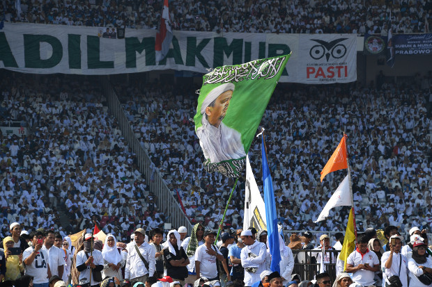 Para pendukung Prabowo Subianto memegang bendera bergambar pemimpin kelompok Islam garis keras, Front Pembela Islam (FPI), Rizieq Shihab, dalam kampanye calon presiden itu di Stadion Gelora Bung Karno di Jakarta, 7 April 2019. (AFP) 